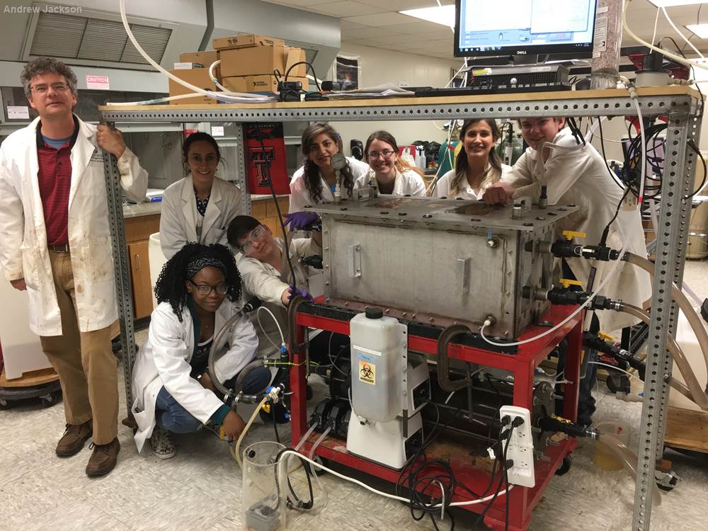 Dr. Andrew Jackson (standing left) and his space habitation wastewater recycling research group around a prototype microgravity compatible bioreactor (CoMANDR). 